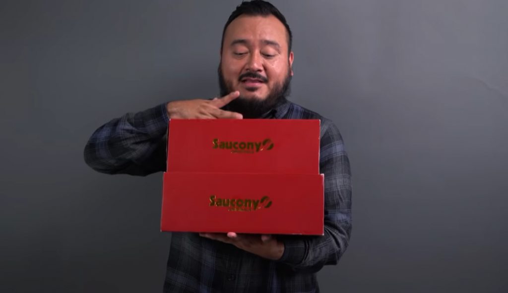 man holding 2 saucony original red boxes